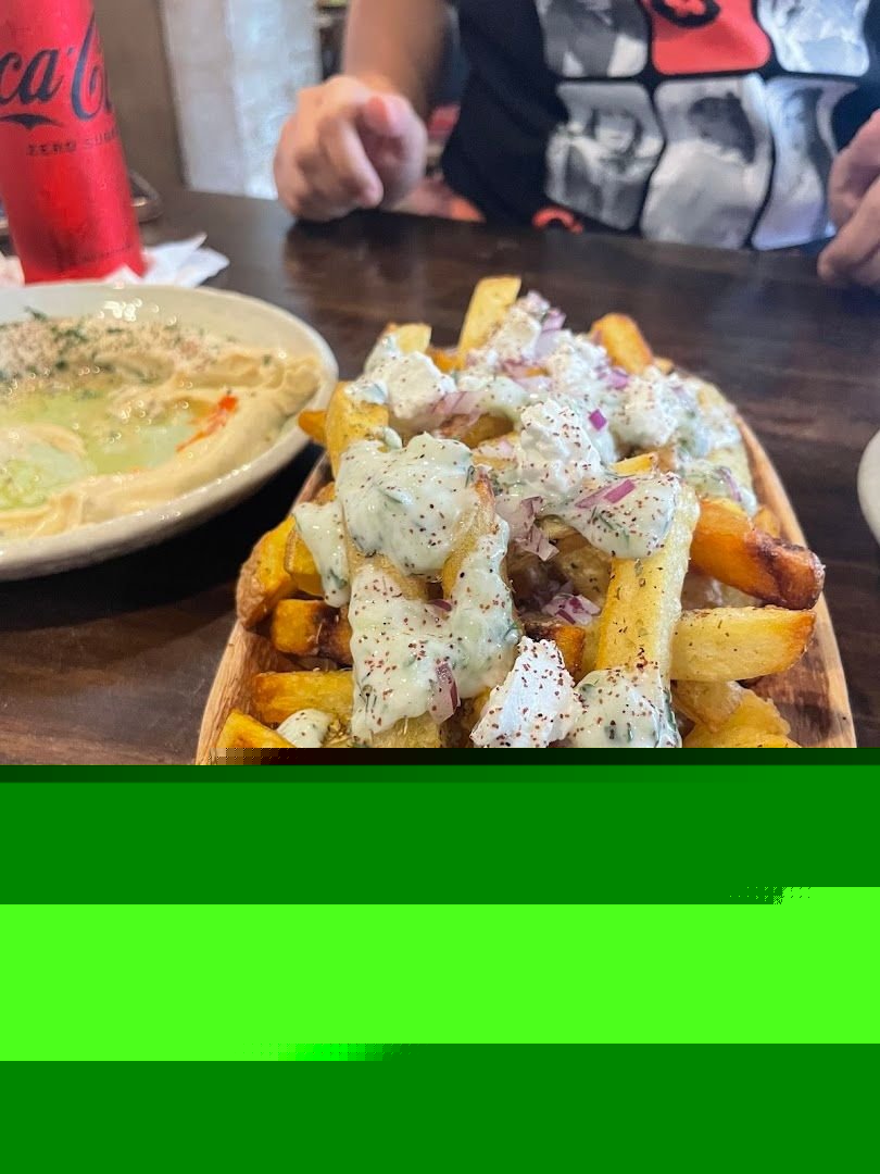 Greek fries topped with feta cheese, tzatziki sauce, red onions, and sumac